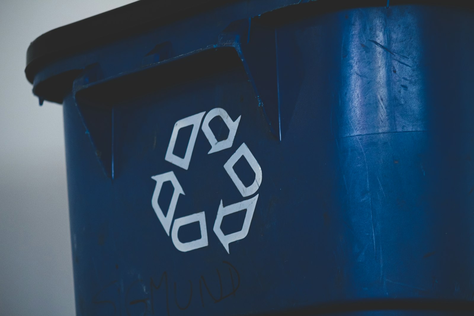 Close-up of a blue recycling wheelie bin with the white recycling symbol
